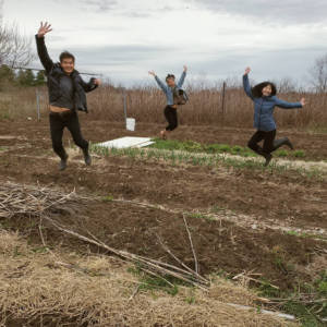 three people jumping into the air with a garden field in the background